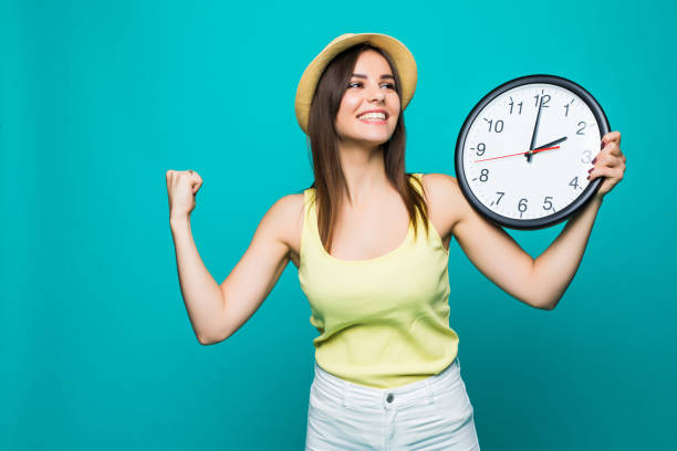 istock Young happy woman holding a clock with 2 clock on a green background 873170374