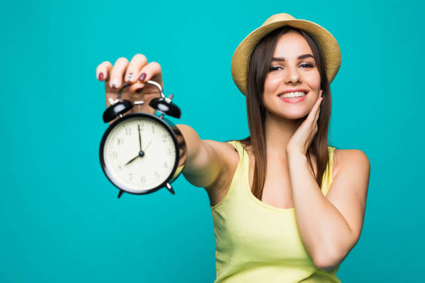 mujer de belleza sonriente sosteniendo alarma en 8 en punto. retrato aislado. - 8 oclock fotografías e imágenes de stock