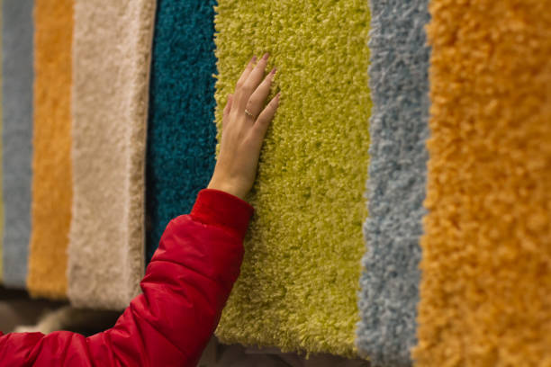 femme passe shopping et sélectionne des tapis en peluche à la main dans le magasin - manufacture de tapis photos et images de collection