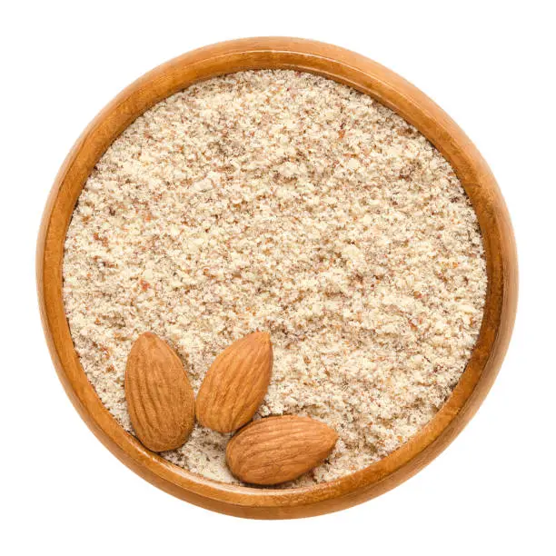 Photo of Shelled and ground almond nuts in wooden bowl over white