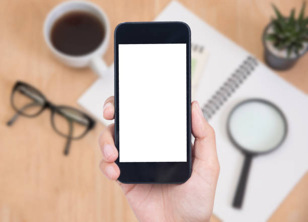 istock Business hand holding smart phone with white screen isolated on desk office background. 873196112