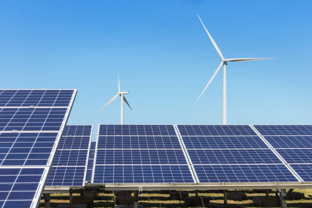 istock Rows array of  polycrystalline silicon solar panels and wind turbines generating electricity in hybrid power plant systems station alternative renewable energy from natural 873196182
