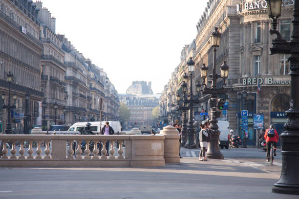 A street view of the Avenue de l'Opera with Solfea Bank on the right and Hotel du Louvre (Hyatt) in the background, Paris PARIS, FRANCE - APRIL 8, 2015: A street view of the Avenue de l'Opera with Solfea Bank on the right and Hotel du Louvre (Hyatt) in the background place de lopera stock pictures, royalty-free photos & images