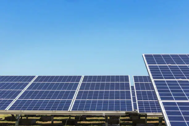 Rows array of  polycrystalline silicon solar cells in solar power plant turn up skyward absorb the sunlight from the sun use light energy to generate electricity alternative renewable energy from the sun on blue sky background