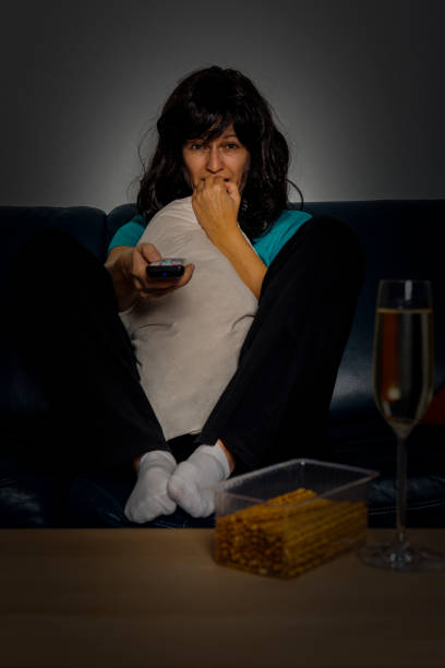 afraid woman with television remote control hiding face