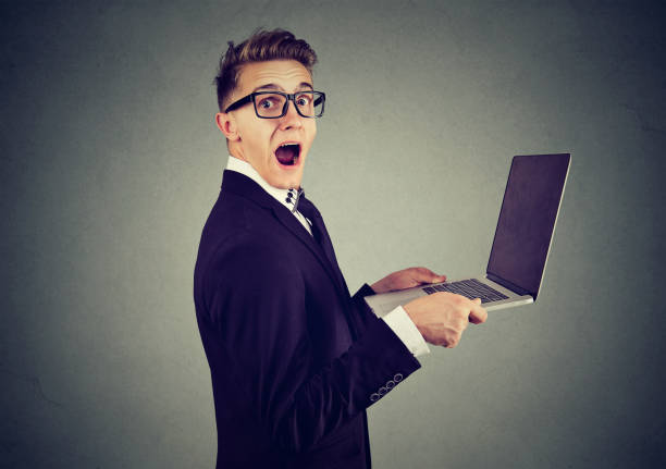 istock Surprised stunned man with laptop computer looking at camera isolated on gray background. 873215870