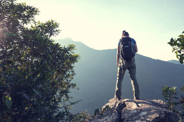 istock successful woman backpacker standing on cliff's edge in the sunrise 873218052