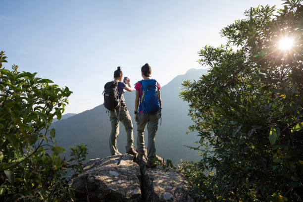 istock two young women backpackers enjoy the view on cliff's edge in the sunrise 873222504