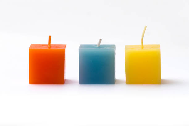istock Three colorful cube candles in a row on white 873226434