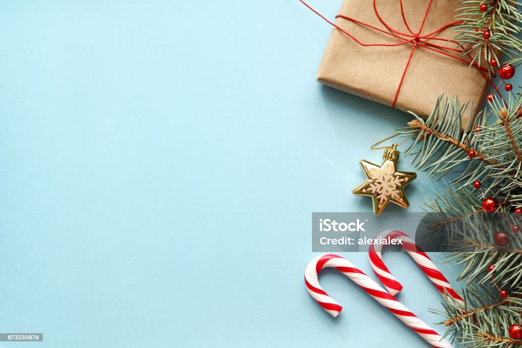 Composition with Christmas gift box, fir tree branch, candy canes. Christmas background. Composition with Christmas gift box, fir tree branch, candy canes and decorations on blue background. Top view with copy space. Christmas Stock Photo