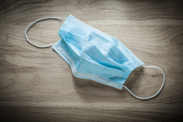 istock Disposable surgical sterile mask on wooden board top view 873238296
