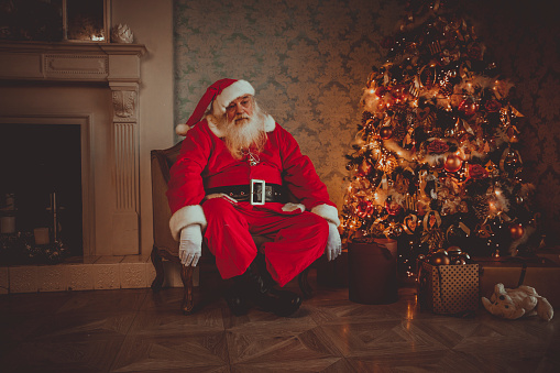 Santa tired asleep in chair near Christmas tree