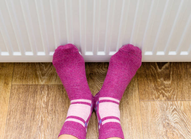 istock Woman warming cold feet in front of heater 873242578