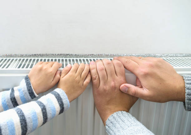istock Father and son heating up a hands in front of a radiator. 873242670