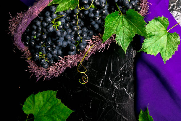 istock Red wine grapes in voiolet basket on bllack background. Top view. Copy space. 873245286