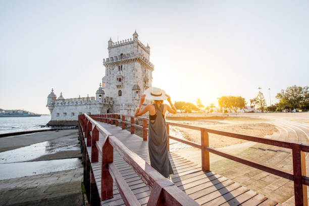 Woman traveling in Lisbon, Portugal Young woman tourist walking on the bridge of the Belem tower on the riverside during the sunset in Lisbon, Portugal historic district photos stock pictures, royalty-free photos & images