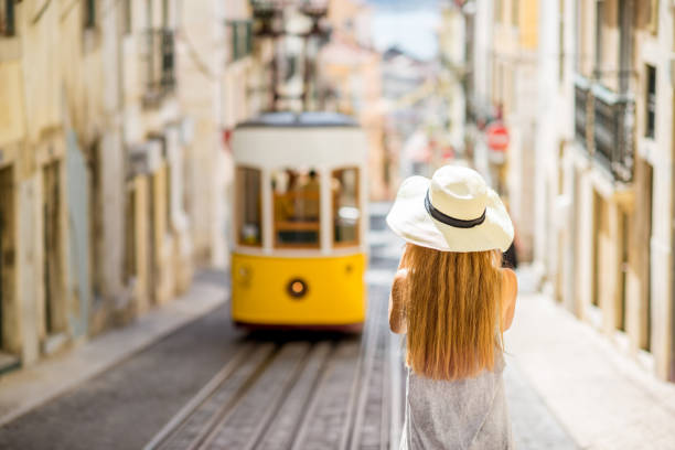 Woman traveling in Lisbon, Portugal Young woman tourist photographing famous retro yellow tram on the street in Lisbon city, Portugal lisbon photos stock pictures, royalty-free photos & images