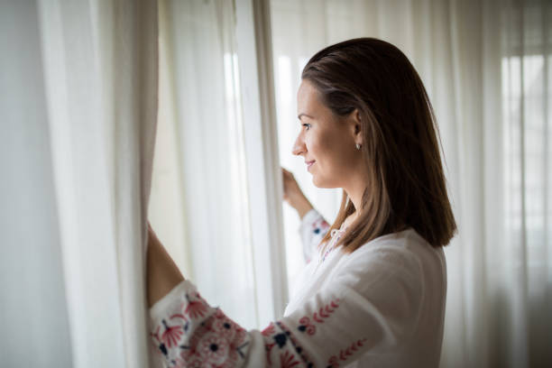 istock Girl looking through the window 873278640
