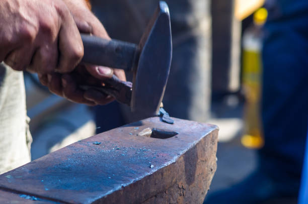 istock blacksmith performs the forging of hot glowing metal on the anvil 873282474