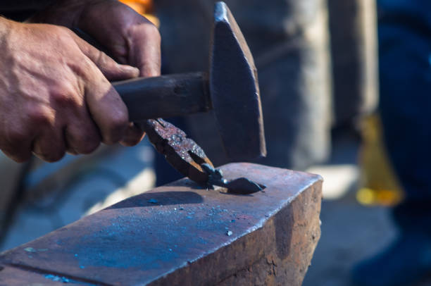 istock blacksmith performs the forging of hot glowing metal on the anvil 873286586