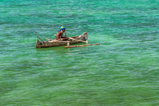 ANAKAO, MADAGASCAR - NOVEMBER 23, 2022: Fishermen using outrigger canoe carved from tree trunk to fish off the coast of Anakao. The primary source of livelihood in Anakao is fishing.