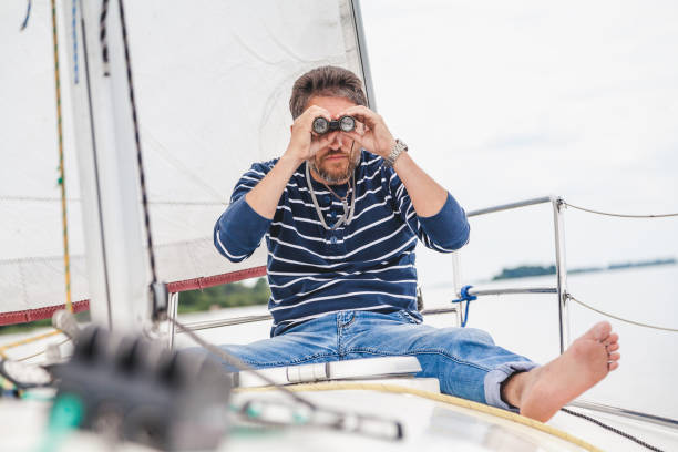 istock man sits on sailing yacht and looks through binoculars 873289918