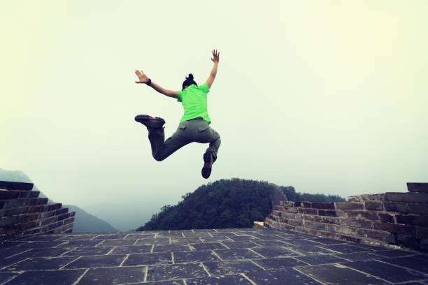 istock successful woman hiker jumping on great wall 873293678