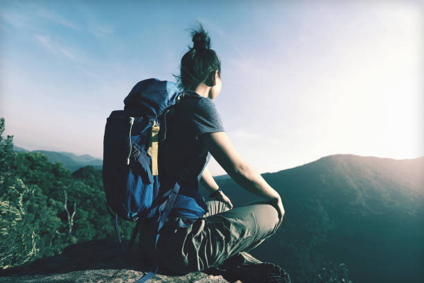 istock young woman backpacker sit on cliff's edge enjoy the view 873309522