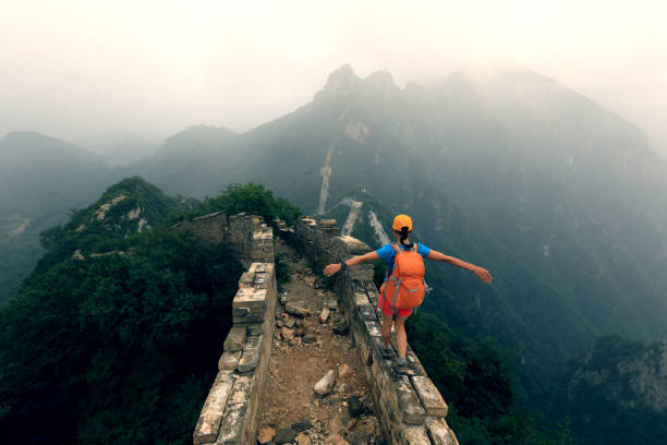 randonneur femme réussi ouvrir les bras à la grande muraille au sommet de la montagne - tourist travel china great wall of china photos et images de collection
