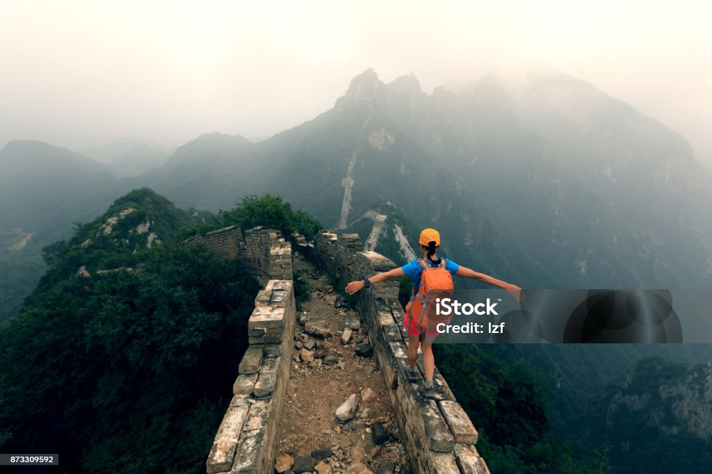 successful woman hiker open arms to the great wall on the top of mountain Great Wall Of China Stock Photo