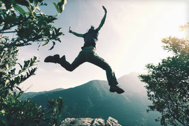 successful young woman jumping on cliff's edge - sunrise asia china climbing imagens e fotografias de stock