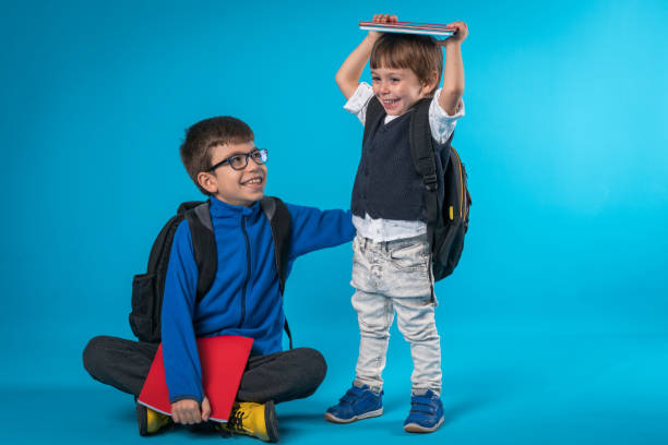 Happy brothers ready for school isolated on colored  background