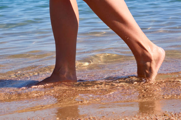 istock Beautiful woman's legs on the beach sand 873314272