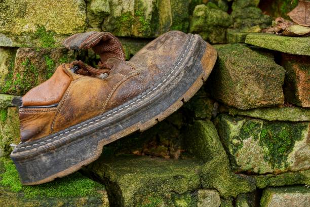 a big old brown boot stands on a stone wall