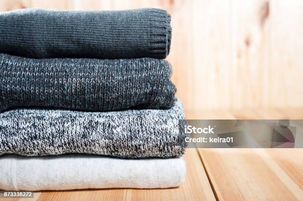 A Neat Pile Of Knitted Warm Blanket Or Sweaters Gray White On A Wooden Background Stock Photo - Download Image Now