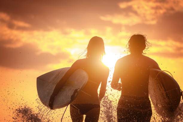 istock Couple of surfers at sunset 873356648