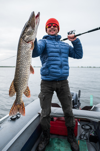 Happy angler holds big pike fish