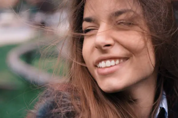 Beautiful charming giirl in a windy weather looking away with adorable smile with messy hair in a cloudyday.