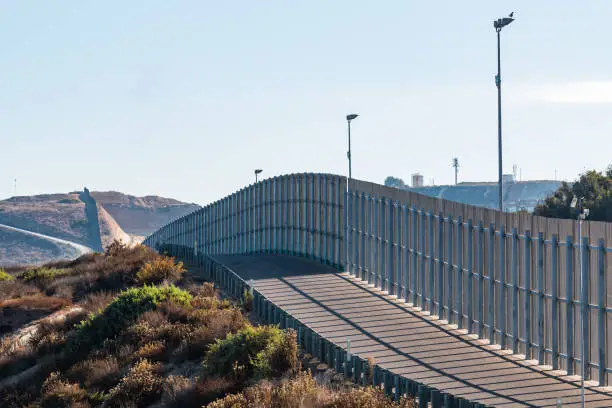 A section of the international border wall between San Diego, California and Tijuana, Mexico, as it travels over rolling hills.