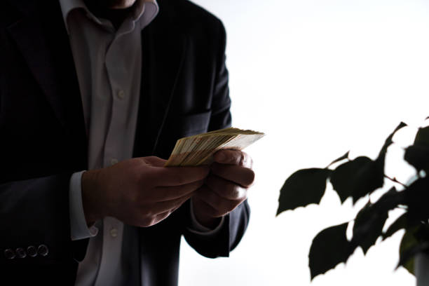 Money laundry, bribery and greediness concept. Businessman or man in a suit holding a stack of money in hand.