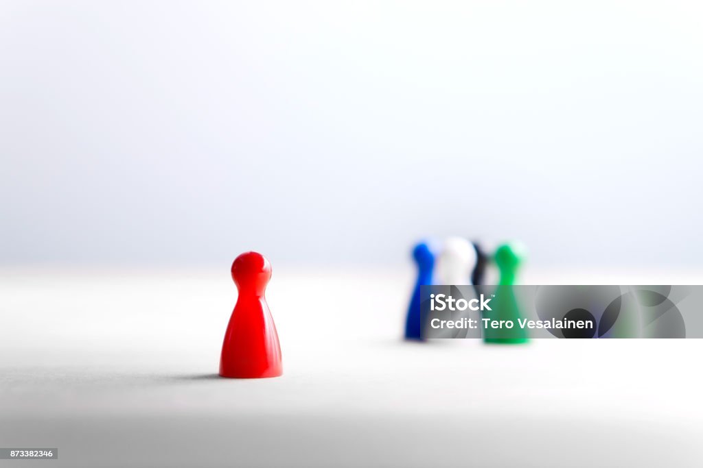 Being alone, outsider and outcast. Racism, discrimination, bullying and social isolation concept. Being alone, outsider and outcast. Racism, discrimination, bullying and social isolation concept. Board game pawns on wooden table. Exclusion Stock Photo