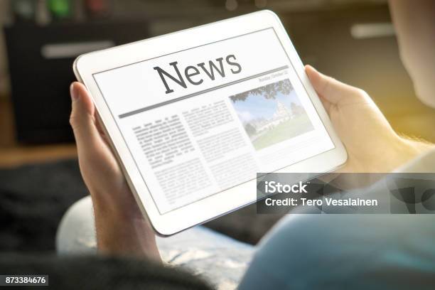 Man Reading The News On Tablet At Home Imaginary Online And Mobile News Website Application Or Portal On Modern Touch Screen Display Stock Photo - Download Image Now