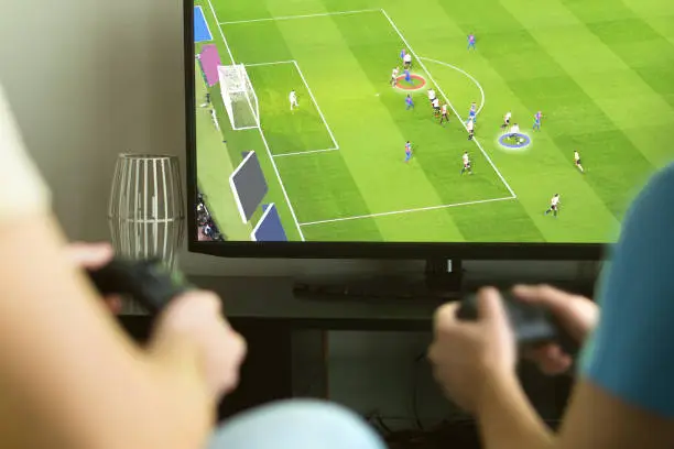 Two guys playing imaginary multiplayer soccer or football video game with console and tv. Guys night, party and weekend concept.