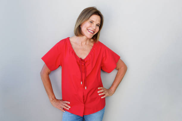 istock smiling older woman against gray wall 873392812