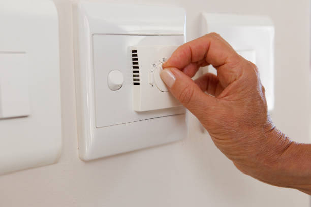 istock woman hand adjusting temperature on dial 873392872