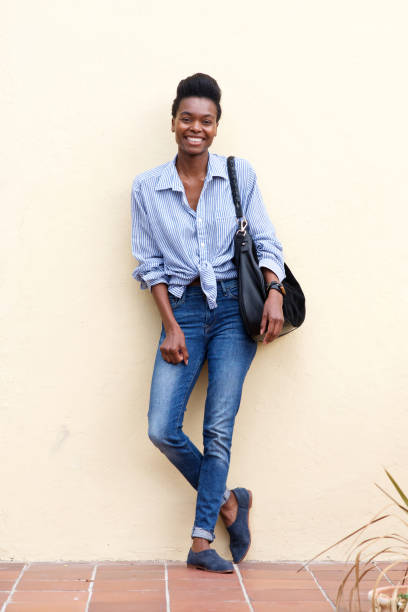 istock smiling black woman leaning against wall 873393078