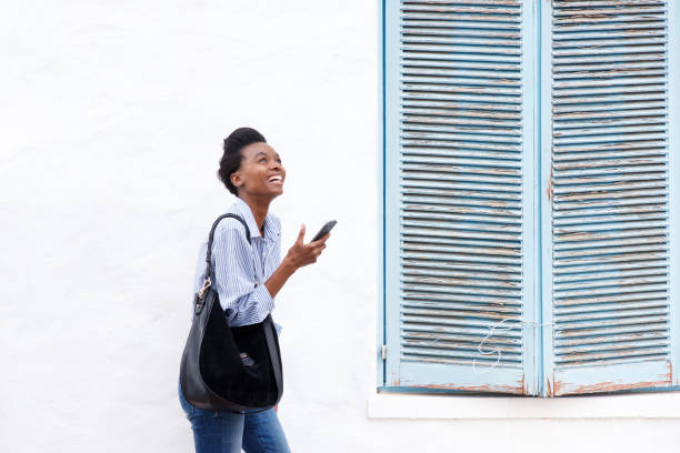 istock cheerful young woman walking with cellphone 873393100