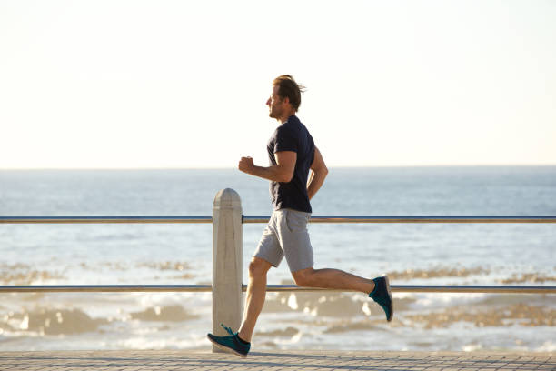 istock side portrait of active man running by sea 873393340