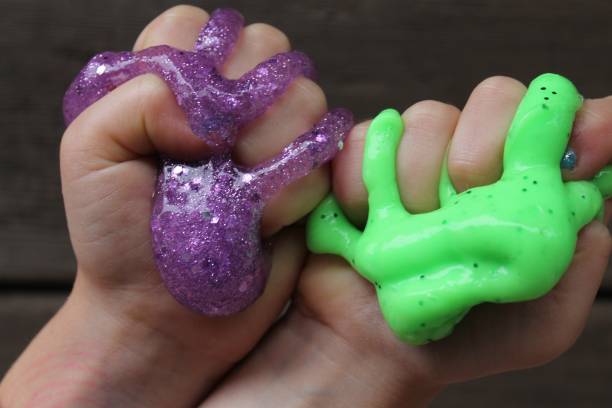 green and purple slime squeezed in child's hands