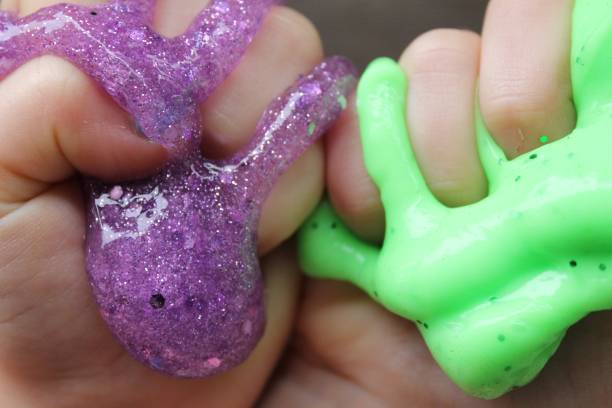 istock green and purple slime squeezed in child's hands 873395524